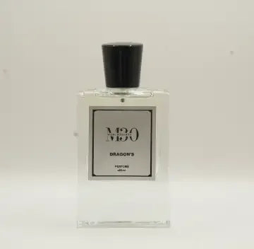 Clear glass bottle of Dragon's perfume with black cap, minimalist label, white background